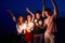 Friends walking, dancing and having fun during night party at the seaside with bengal sparkler lights in their hands