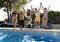 Friends young happy attractive men women in bikini jumping in the air to hotel swimming pool