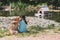 Friendship of animals and children, people. Caucasian girl sits on the bank of a pond, river and hugs a labrador puppy. Outdoor