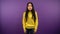 Frightened Asian woman in yellow sweater clutches her head. woman on purple isolated background. 4K