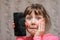 The frightened child accidentally ruined the smartphone. Portrait of a scared little girl with a broken mobile phone. A sad child