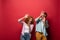 Frightened couple gesturing in casual clothes isolated on red