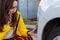 Frightened and helpless woman looking at her damaged scratched car