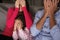 Frightened Hispanic Family Sitting On Sofa And Watching TV