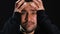 Frightened man holding head isolated on black background, horror scene, close-up