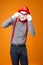 Frightened mime in vest and red hat on orange background.
