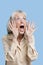 Frightened senior woman screaming against blue background