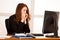 Frightened stressed woman working at her desk in the office, reading bad report.