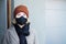 Frightened and worried teenage girl wearing a black protenctive sanitary mask enters a house during second lockdown in coronavirus