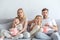 Frightened young family watching scary movie on couch