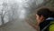 A frightened young girl walks along an abandoned old road in a misty forest. Blogger is broadcasting a dangerous walk