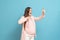 Frightened young pregnant woman on blue background calls by mobile phone, discharge of amniotic fluid, the beginning of labor