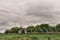 Frightening abandoned and overgrown ruins of agricultural buildings on a rural farm in the fields under a cloudy sky