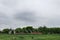 Frightening abandoned and overgrown ruins of agricultural buildings on a rural farm in the fields under a cloudy sky