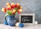 `FrÐ¾he Ostern` in German means Happy Easter Red-yellow tulips in classic blue ceramic pitcher with Easter eggs and a blackboard