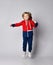 Frolic happy laughing blond kid boy in blue and red sport suit hoodie, trousers and sneakers jumps waving arms