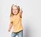 Frolic smiling kid baby girl in yellow t-shirt is having fun good time showing thumb up sign, good job, everything cool
