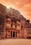 Front of Al-Khazneh Treasury temple carved in stone wall - main attraction in Lost city of Petra, orange sunset sky above