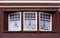 Front beautiful old house facade pattern from red brick with white window frame and retro curtains. Vintage building. Netherlands