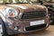 The front of the body is a polished bumper and hood with a brown car brand sign. Mini Cooper model with close-ups of beige gold