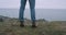 In front of the camera closeup tourist walking to the mountain shore and admire the landscape of mountain and ocean.