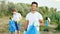 In front of the camera smiling large Afro American guy holding a blue plastic bag he collecting rubbish form the beach