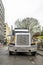 Front of classic big rig semi truck with tip trailer standing on the city work side street at rainy weather