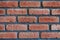 Front close view of a red brick wall corner. Close up of cracked weathered brickwork material. Modern surface indoors, stylish