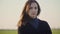 Front closeup portrait of young mixed race caucasian white woman with long brown hair standing against green field and