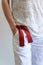 Front crop view of young fashionable woman dressed with white lien pants, t shirt and a red belt