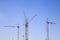 Front distant view of three cranes on a light blue sky background