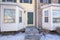 Front door facade of a townhouse with bay windows and snow-covered yard