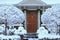 Front door, surrounded by snow covered bushes and trees