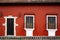 front door and windows with safety bars in a red painted small, old house in Guatemala