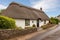 front elevation of a stone cottage, thatched roof, cobblestone driveway