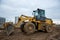 Front-end loader working at construction site. Earth-moving heavy equipment for road work. Public works, civil engineering,