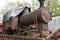 Front-end view on discarded rusty freight steam locomotive loaded on old wagon.