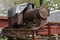 Front-end view on discarded rusty freight steam locomotive loaded on old wooden wagon.