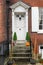 the front of an english house with a single carved pumpkin or jack-o-lantern on the step