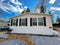 Front entrance view of brand new prefab mobile home with for sale yard sign post near Rochester, New York