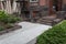 Front entry to old brownstone building with stairs up and down, well maintained landscaping