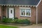 Front exterior of a luxurious dutch bungalow with a garden, front door with decorated window, home in a small village of the