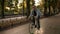 Front footage of a young smiling man in sunglasses cycling a bicycle in the morning park or boulevard. Slow motion of
