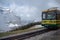 The front of green with yellow hiking train, Jungfrau, with beautiful view of foggy mountain  background