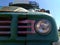 Front headlamp and grill or an old rusty bus with green hood luggage rack on the roof and blank destination board