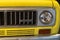 Front headlight, grill and tire of a 1974 International Scout truck car, in yellow