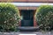 Front house entrance with large green wooden door, bull nose corrugated verandah roof, lace ironwork and two white camellia bushes