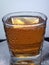 Front image of Full glass of Carbonated fizzy drink wine whiskey apple  with a white and silver background and drops of water