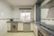 Front image of a kitchen with wooden furniture, integrated stainless steel appliances, white aluminum sash window, microwave oven