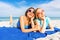 Front low view of Two happy beautiful girls lying on the tropical beach in summer vacation kissed by the sun with sunglasses